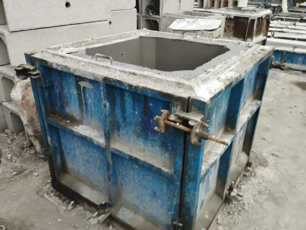 Cetakan beton precast berwarna biru untuk saluran air atau manhole cover, di lokasi produksi.